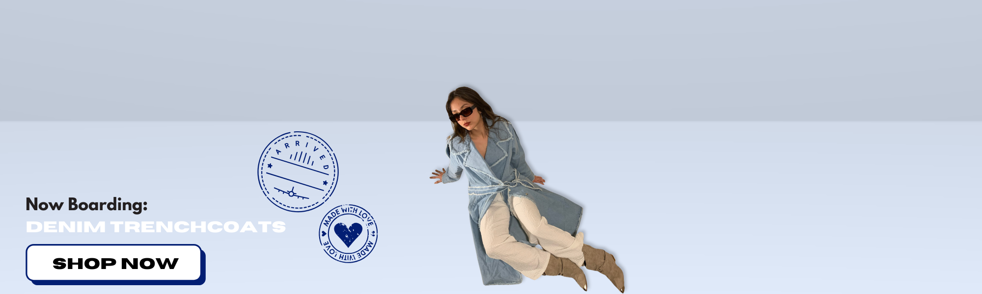 Model lying in front of light blue background. Model is wearing blue denim trenchcoat, white pants, sunglasses , and beige boots.